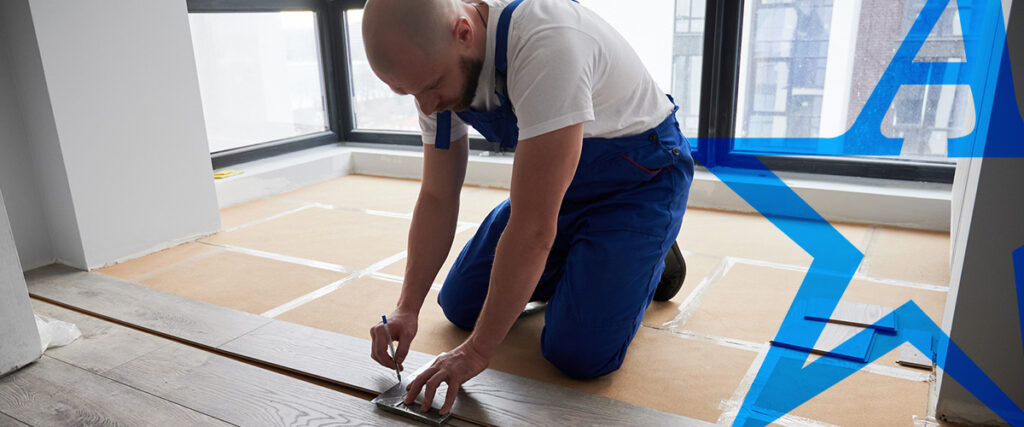 a man in blue overalls is working on a wooden floor